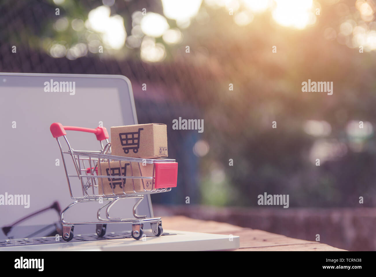 Shopping online concept - Parcel or Paper cartons with a shopping cart logo in a trolley on a laptop keyboard. Shopping service on The online web. off Stock Photo