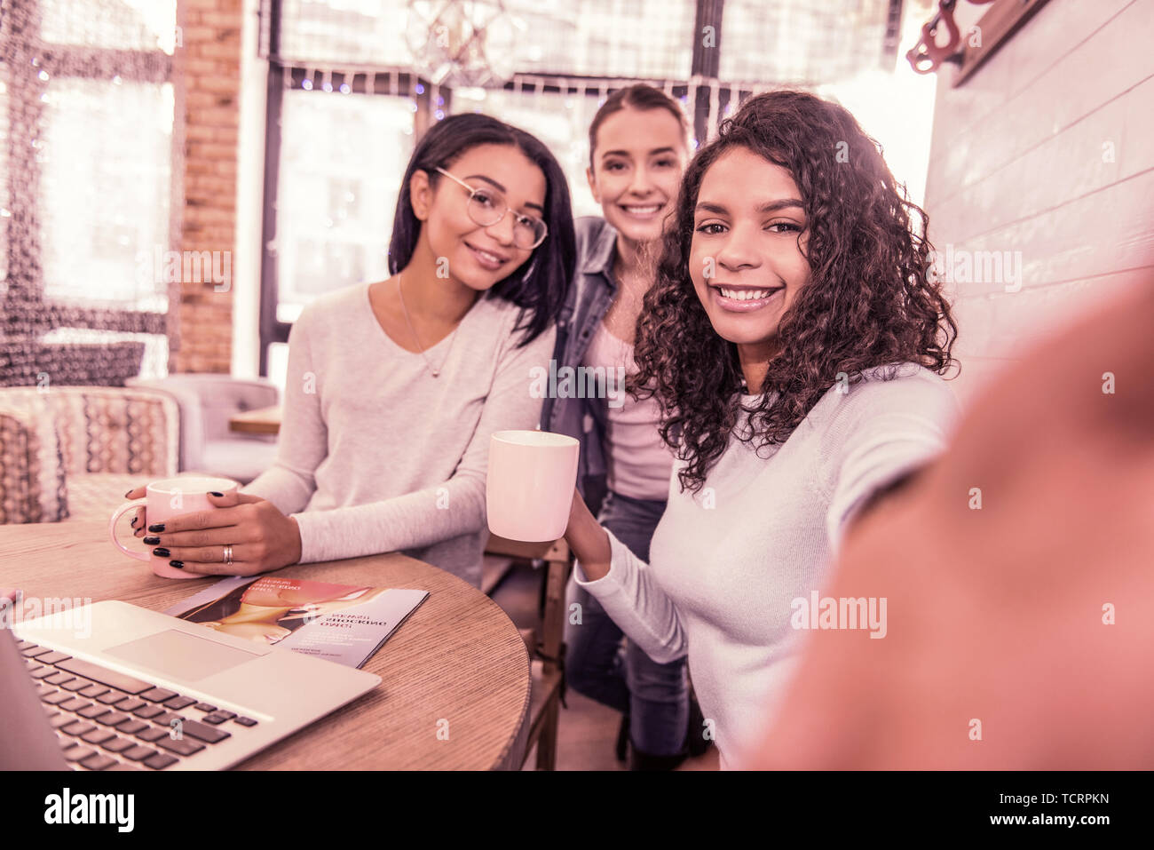 Three beaming women smiling while making photo spending morning in bakery Stock Photo
