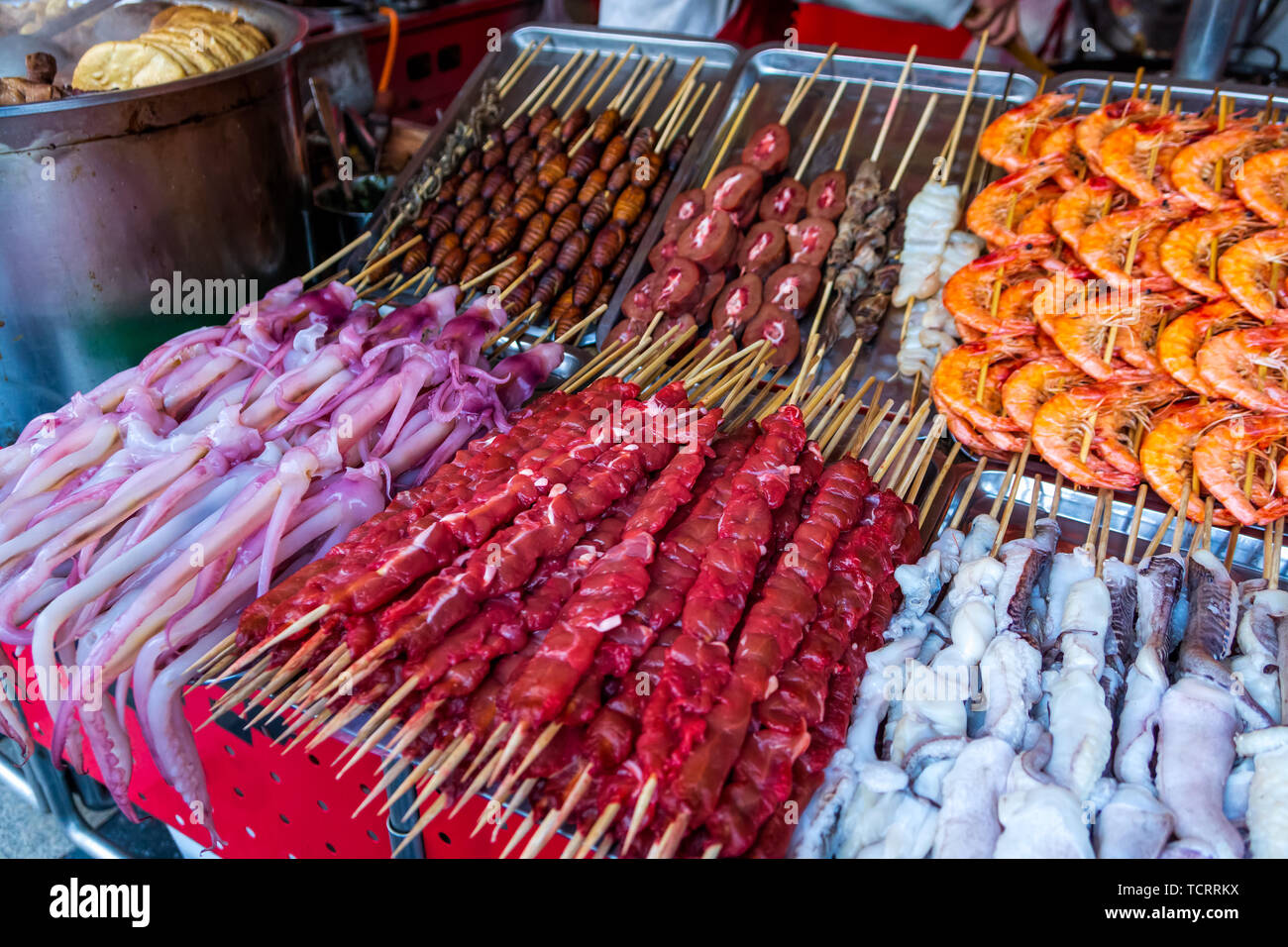 Roasted, fried and raw insects, silkworms, scorpions, bugs, snakes, dog meat, shrimps, octopus on stick as snack street food in China Stock Photo