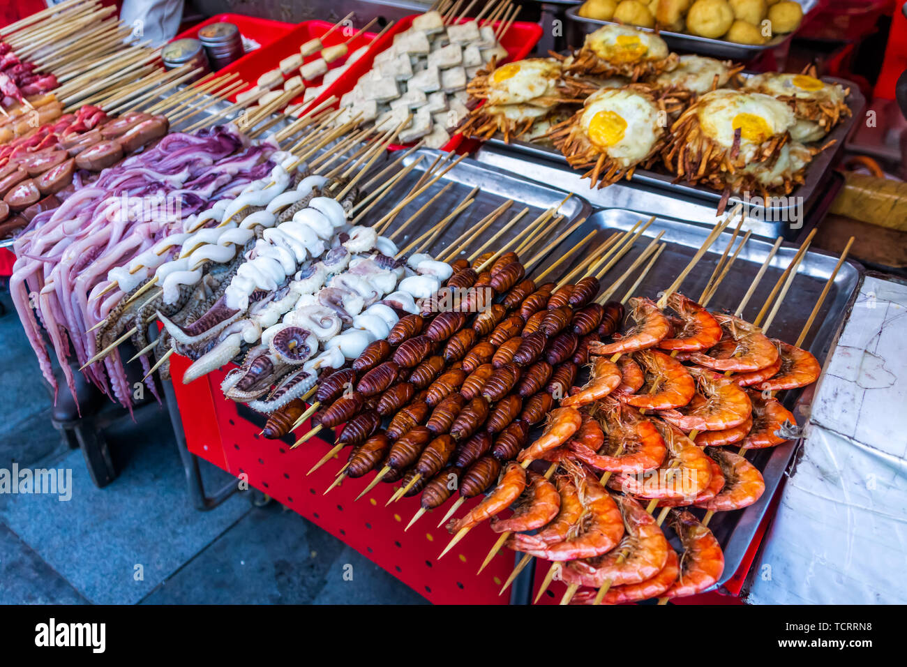 Roasted, fried and raw insects, silkworms, scorpions, bugs, snakes, dog meat, octopus on stick as snack street food in China Stock Photo