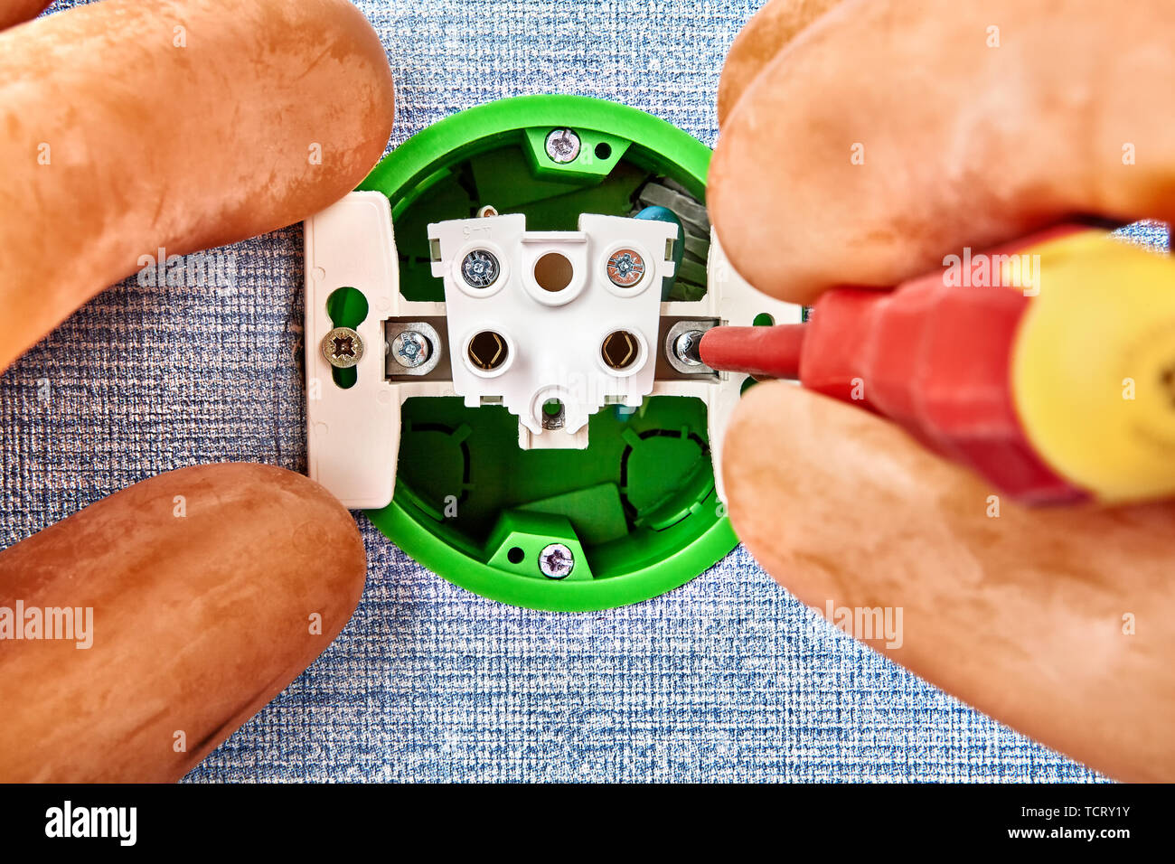 Repairman is replacing electrical outlet in house electrical wiring