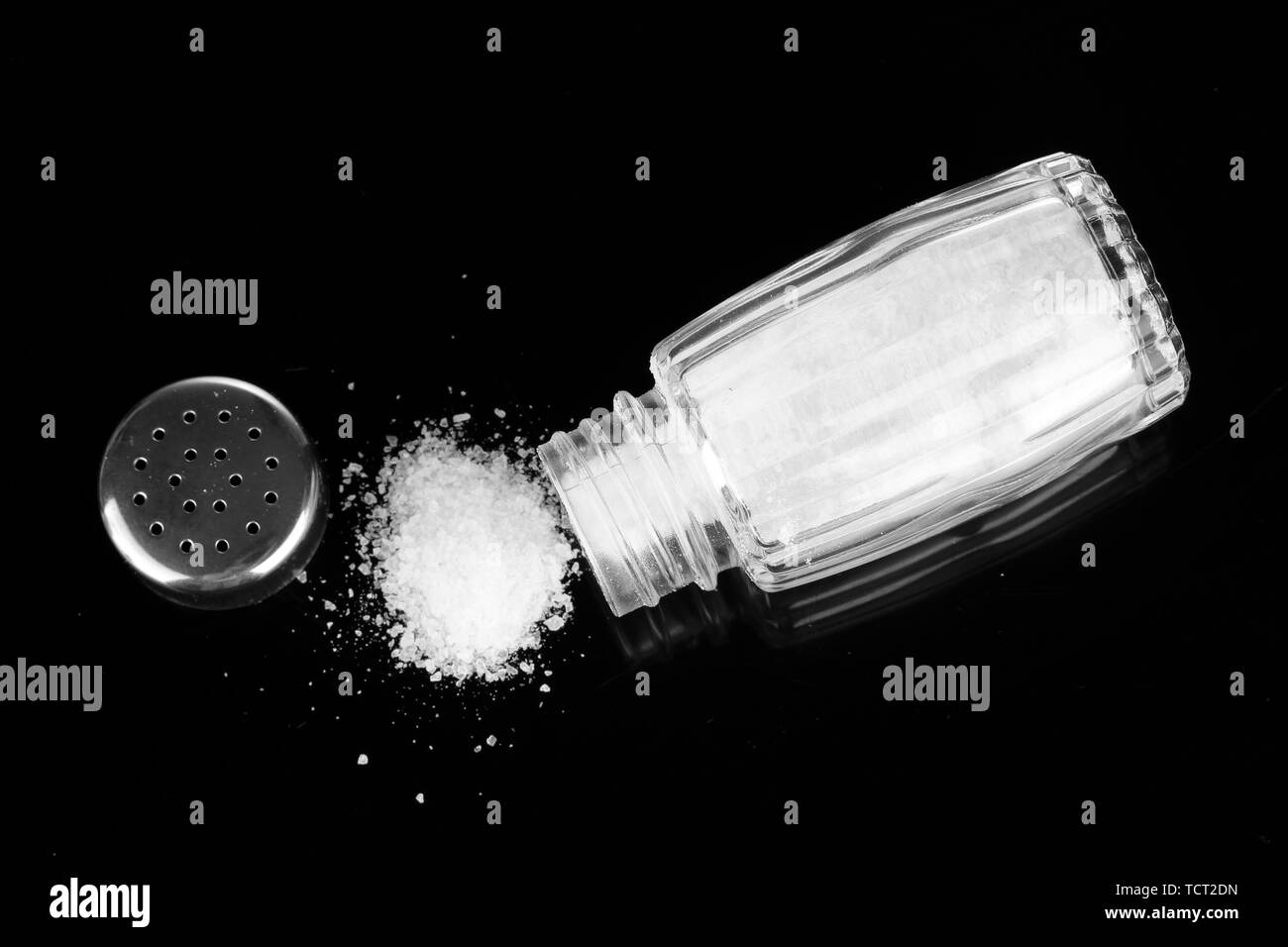 Salt shaker with spilled salt isolated on black Stock Photo Alamy