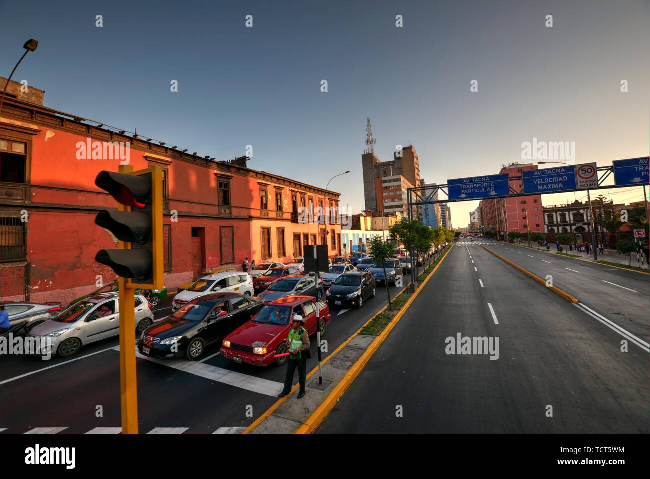 Lima, Peru - April 21, 2018: Early evening traffic lining up at red stop sign with traffic police officer Stock Photo