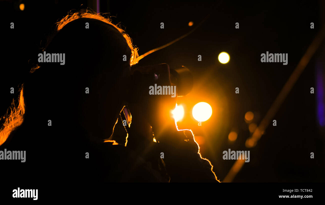 Photographer silhouette taking photos of concert at night Stock Photo