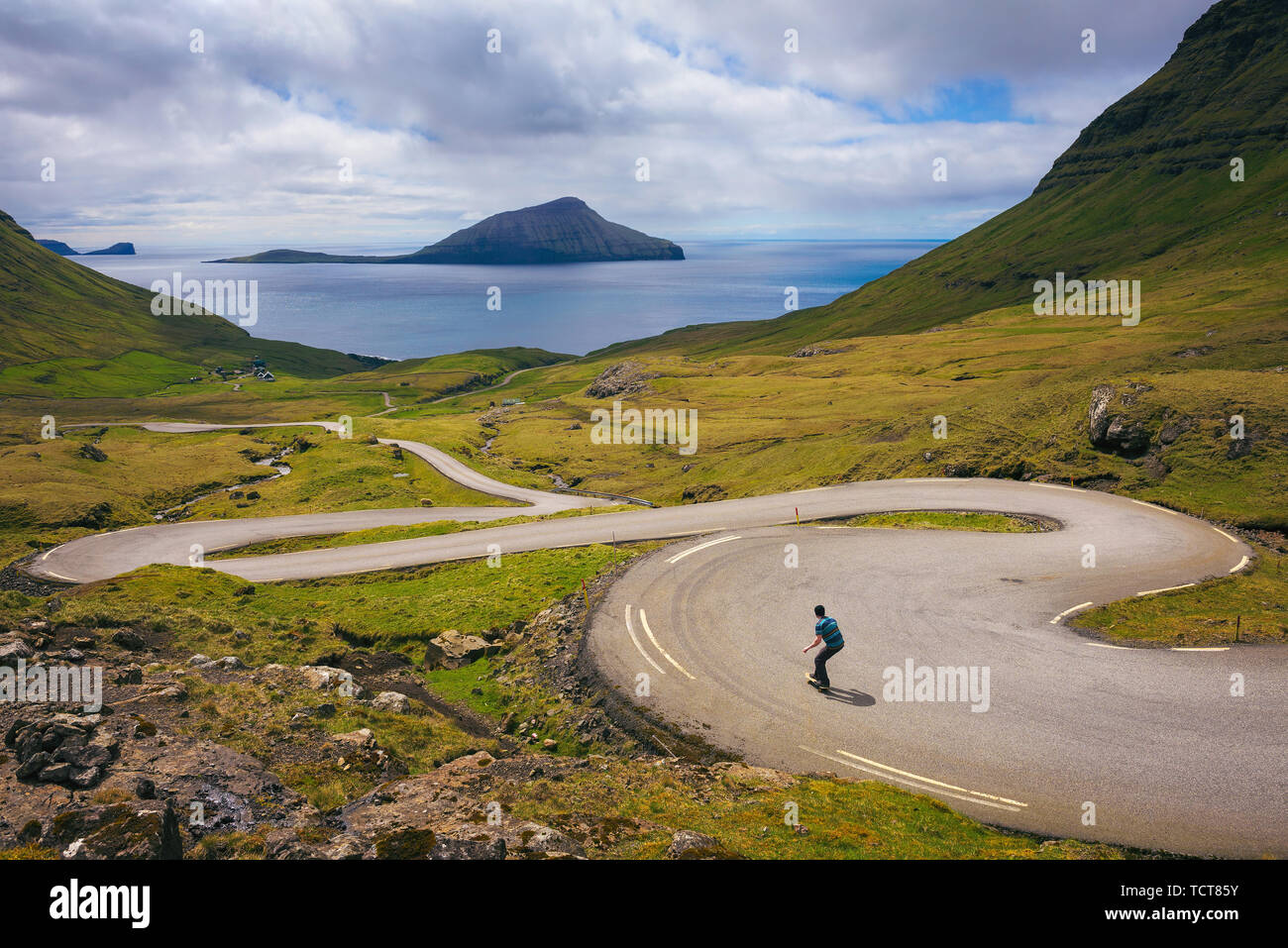 Young skater riding a skateboard through beatiful scenery of Faroe Islands Stock Photo