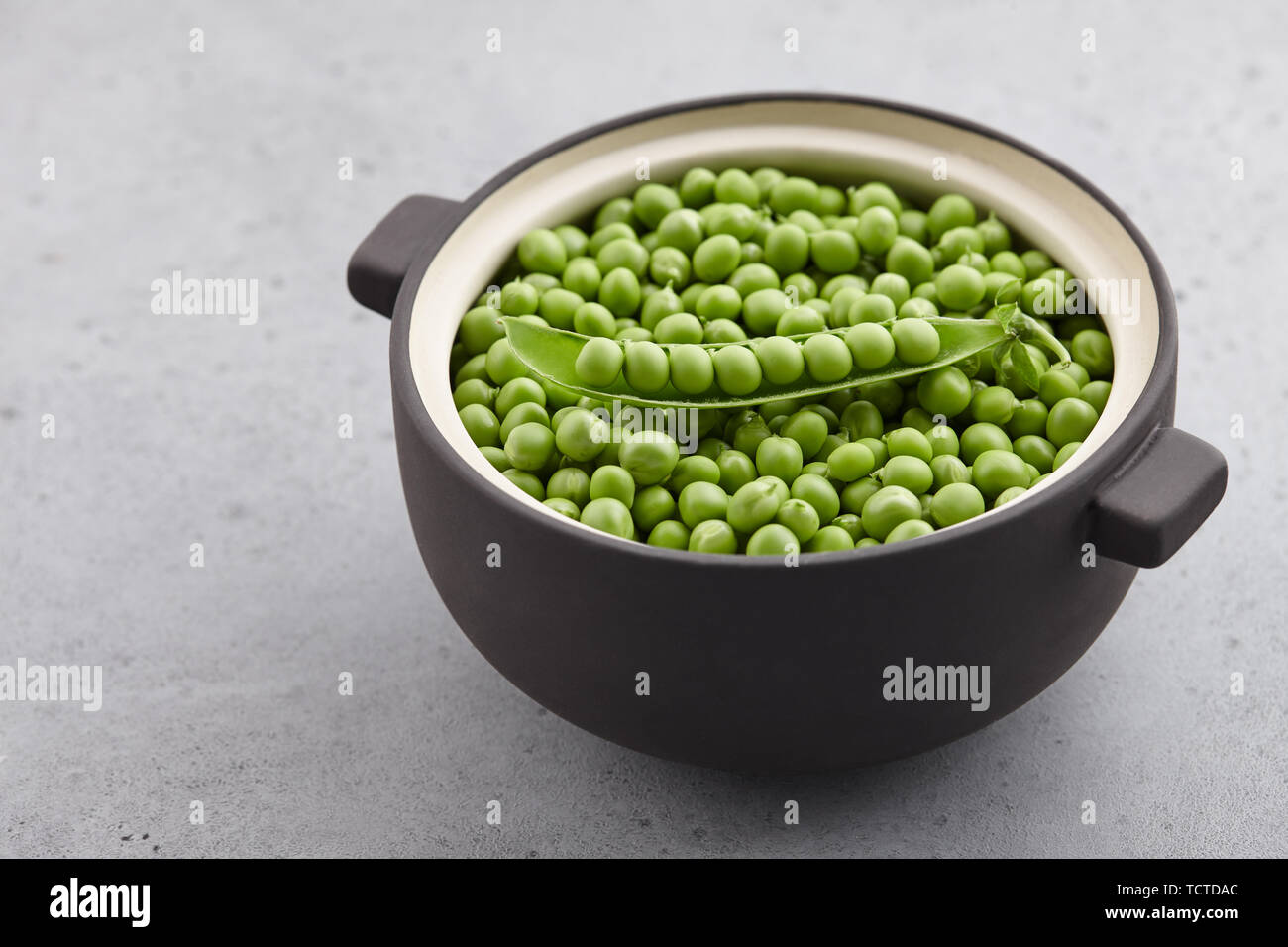 Fresh green peas in big ceramic pot Stock Photo