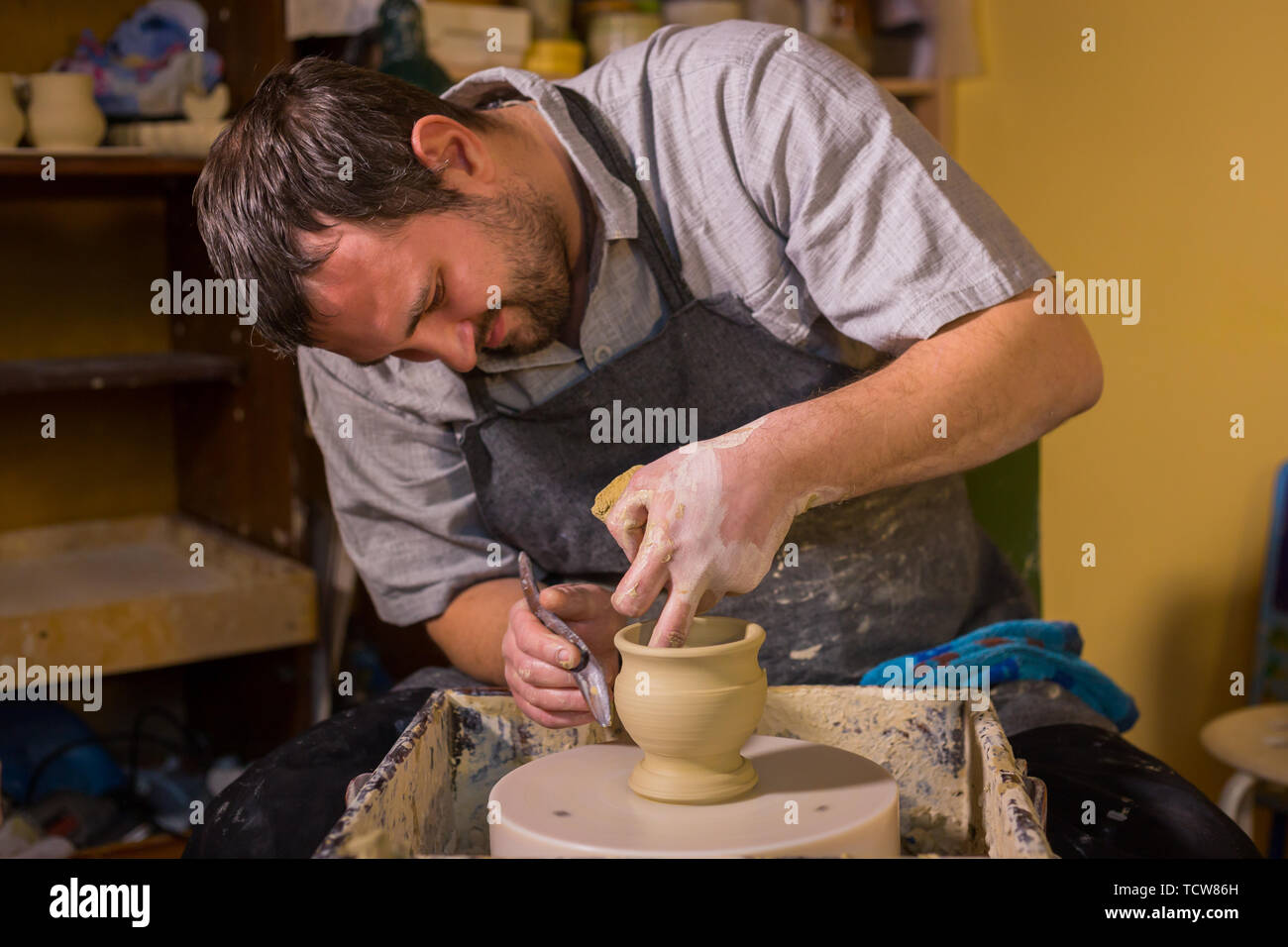 Professional male potter working with clay on potter's wheel Stock Photo