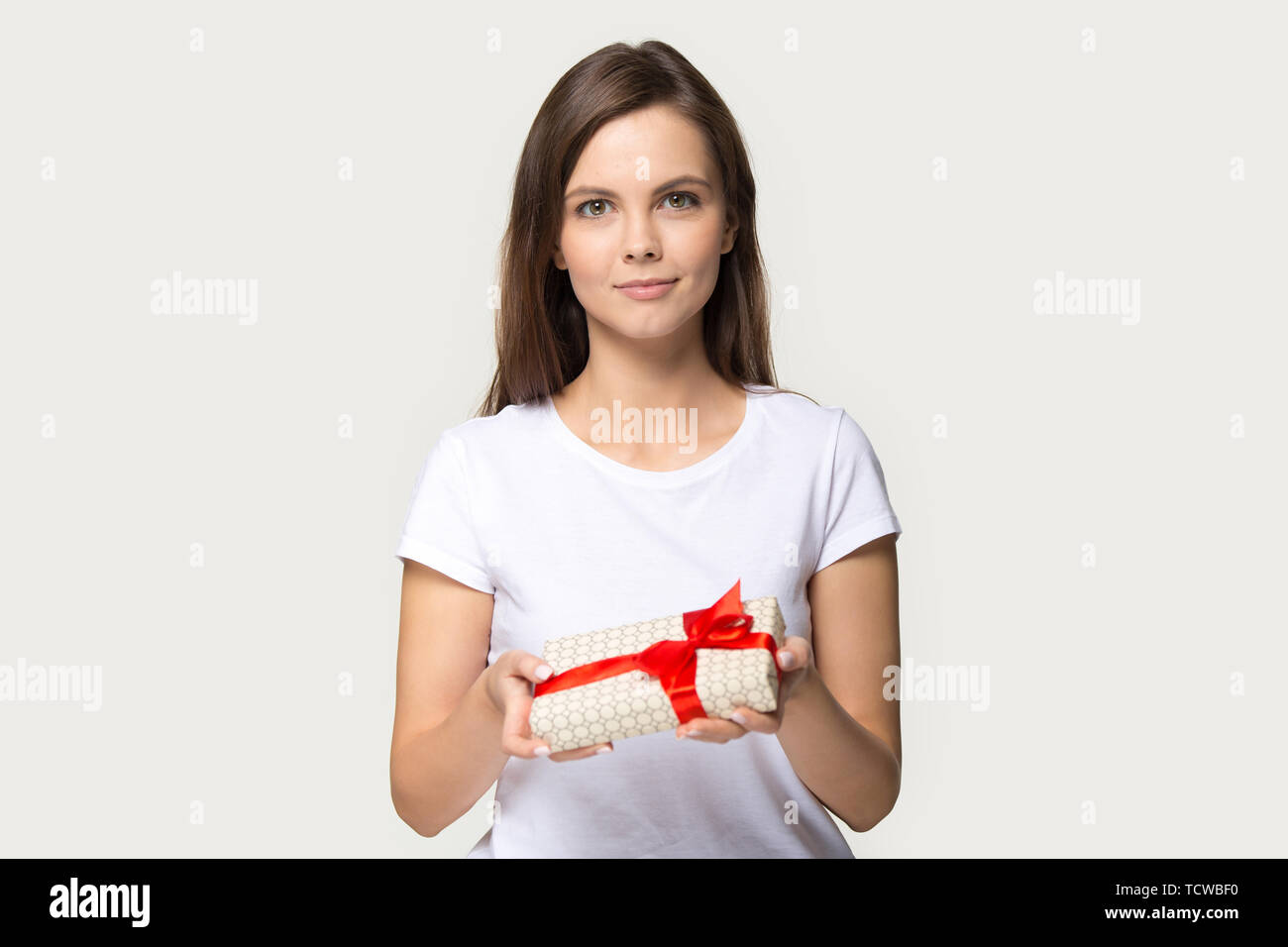Millennial woman holding gift box looking at camera studio shot Stock Photo