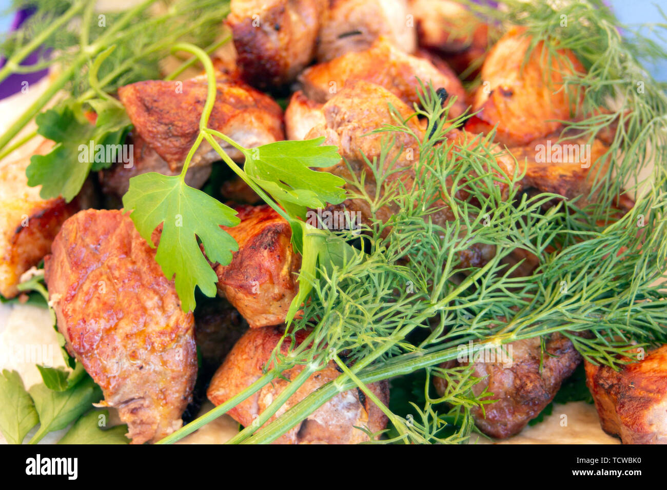 Chopped  bbq pieces of  mutton, beef or chicken meat on the plate with greenery of parsley and dill Stock Photo