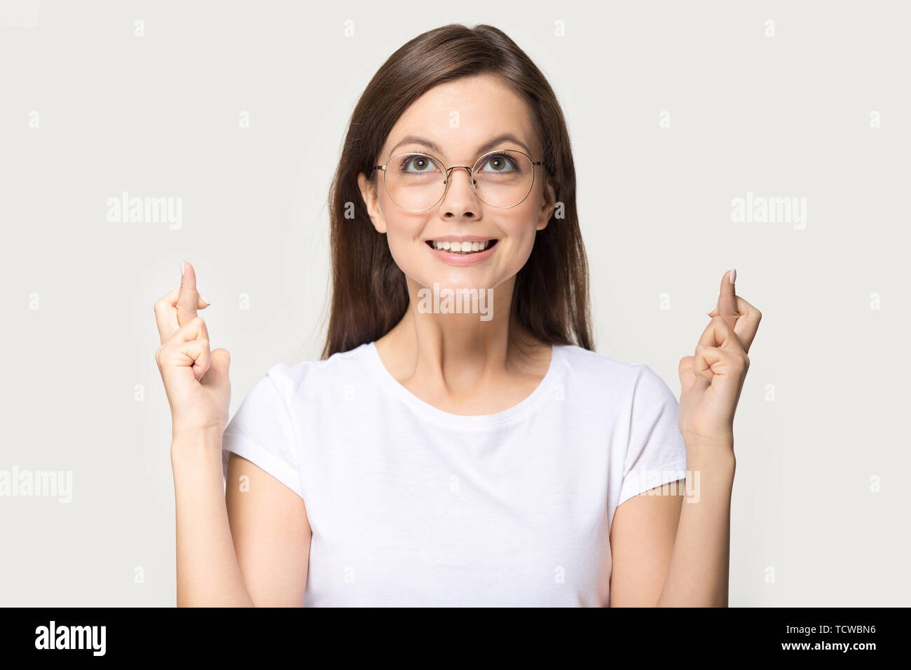Comical woman in glasses crossing fingers asks for good luck Stock Photo