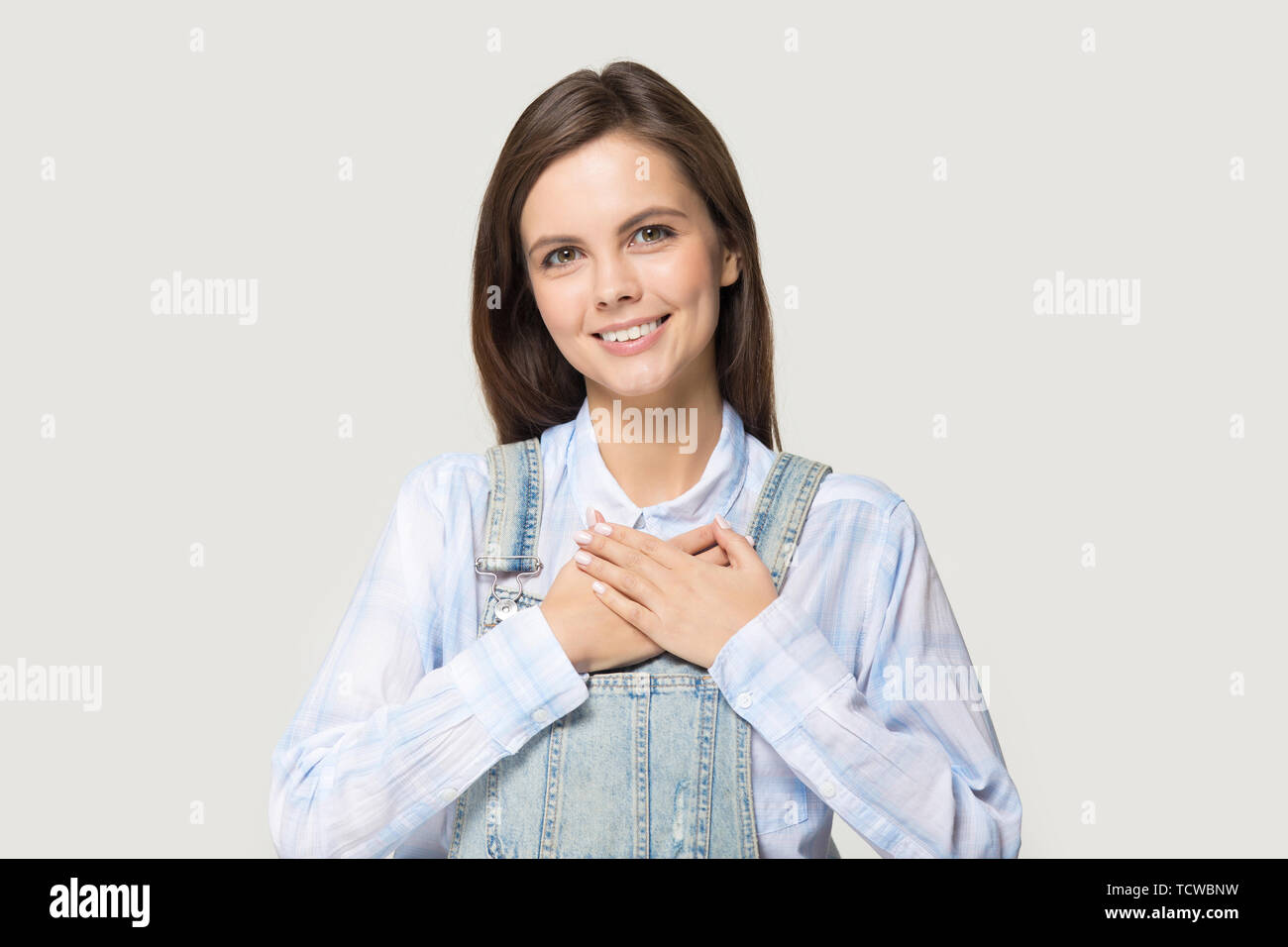 Attractive young woman holding hand on heart feels gratitude Stock Photo