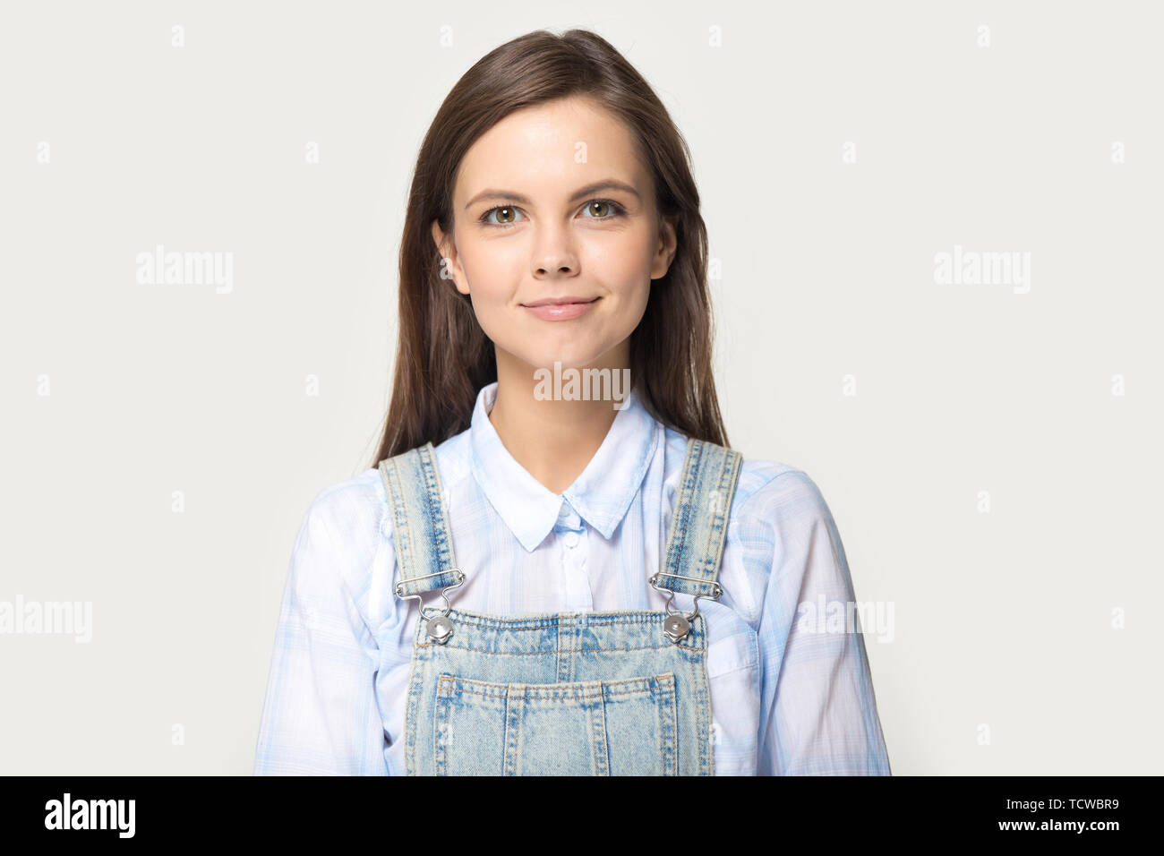 Woman wearing shirt denim coverall posing on grey studio background Stock Photo