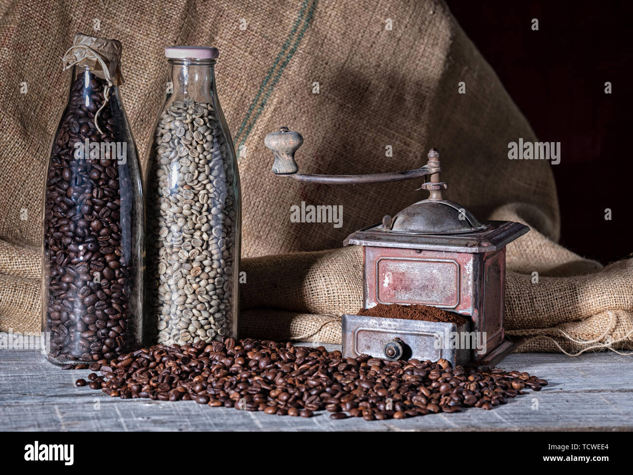old coffee grinder and two glass bottles with different coffee beans Stock Photo