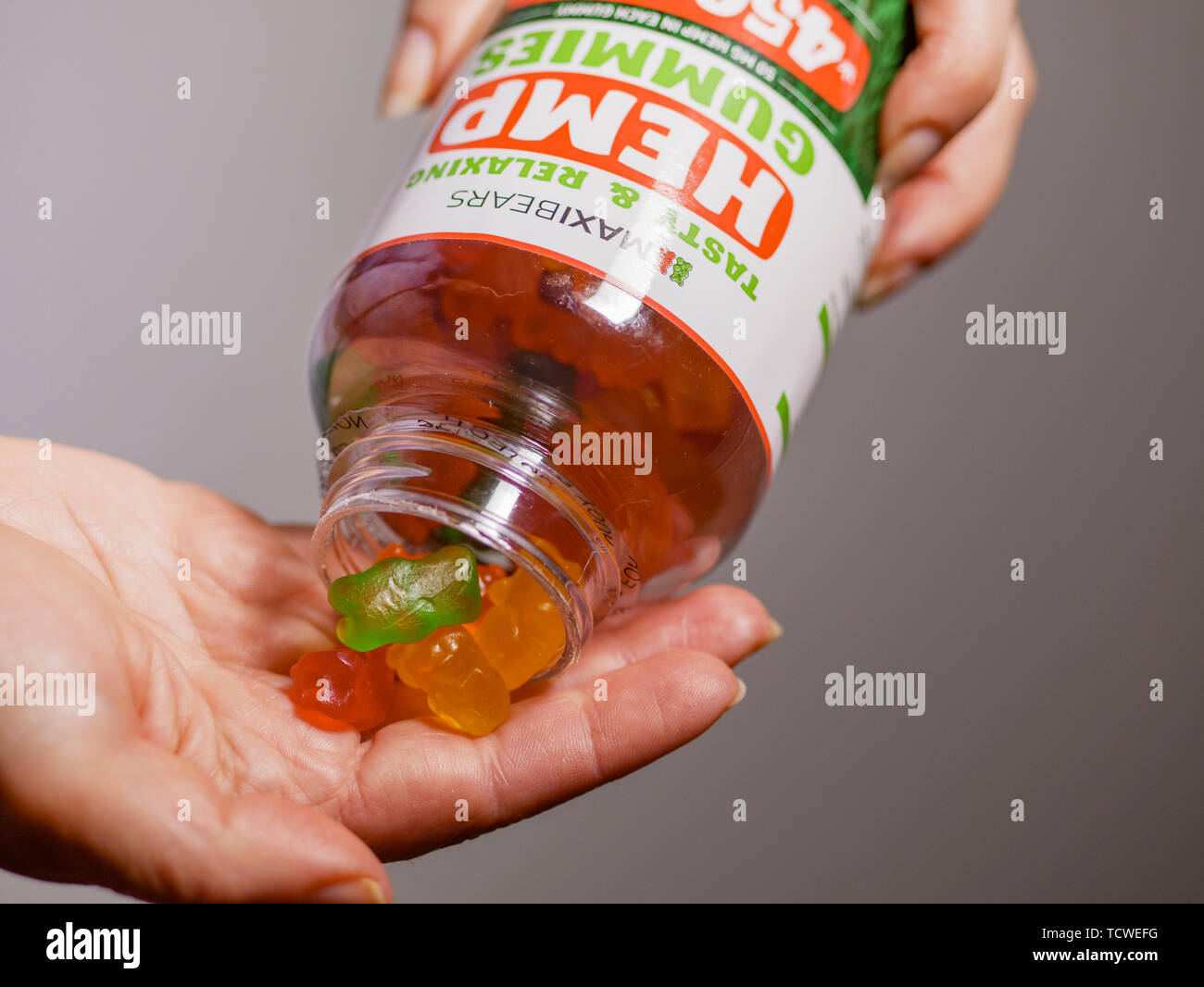 Hands dispensing CBD hemp oil gummies from bottle. Stock Photo