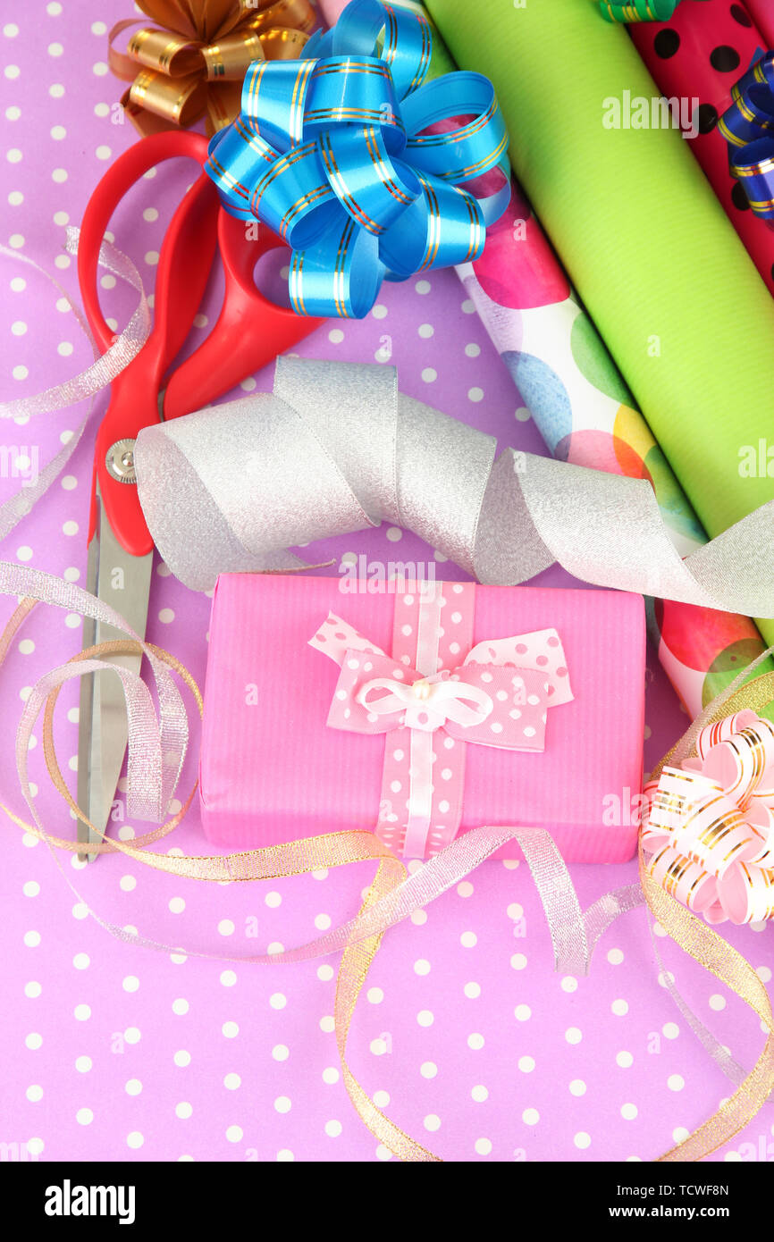 Rolls of Christmas wrapping paper with ribbons, bows on color