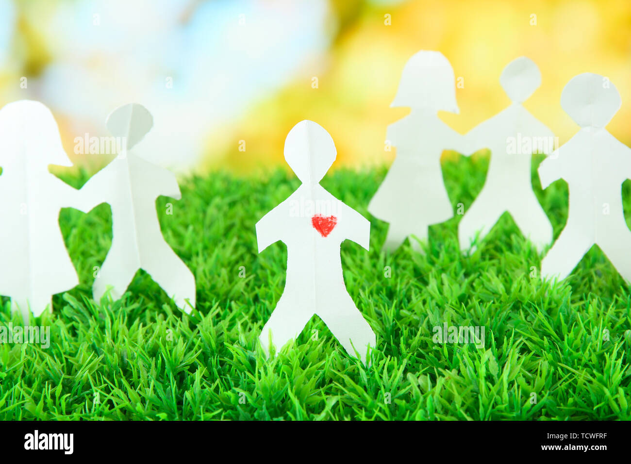 Paper people on green grass on bright background Stock Photo - Alamy