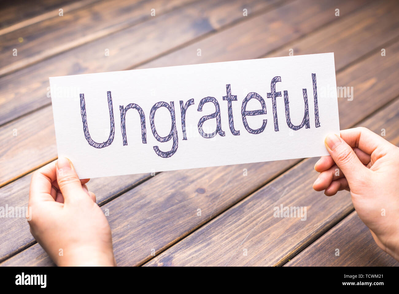 hands hold white paper with word ungrateful Stock Photo