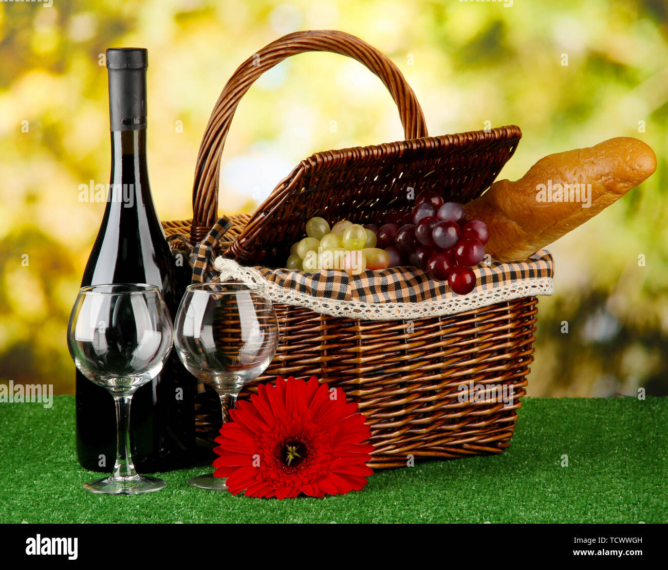 Picnic basket and bottle of wine on grass on bright background Stock ...