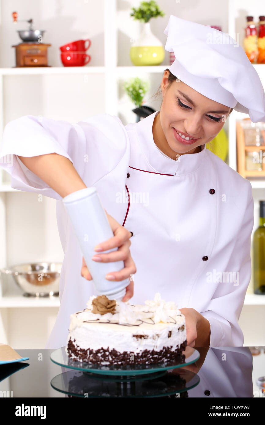 Young woman chef cooking cake in kitchen Stock Photo