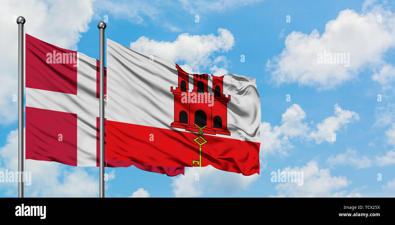 Denmark and Gibraltar flag waving in the wind against white cloudy blue sky together. Diplomacy concept, international relations. Stock Photo
