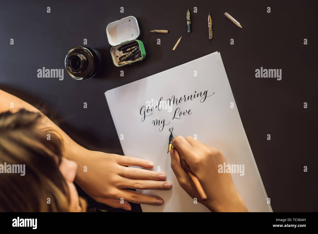 Good Morning In Calligraphy Good morning. Calligrapher Young Woman writes phrase on white paper ...