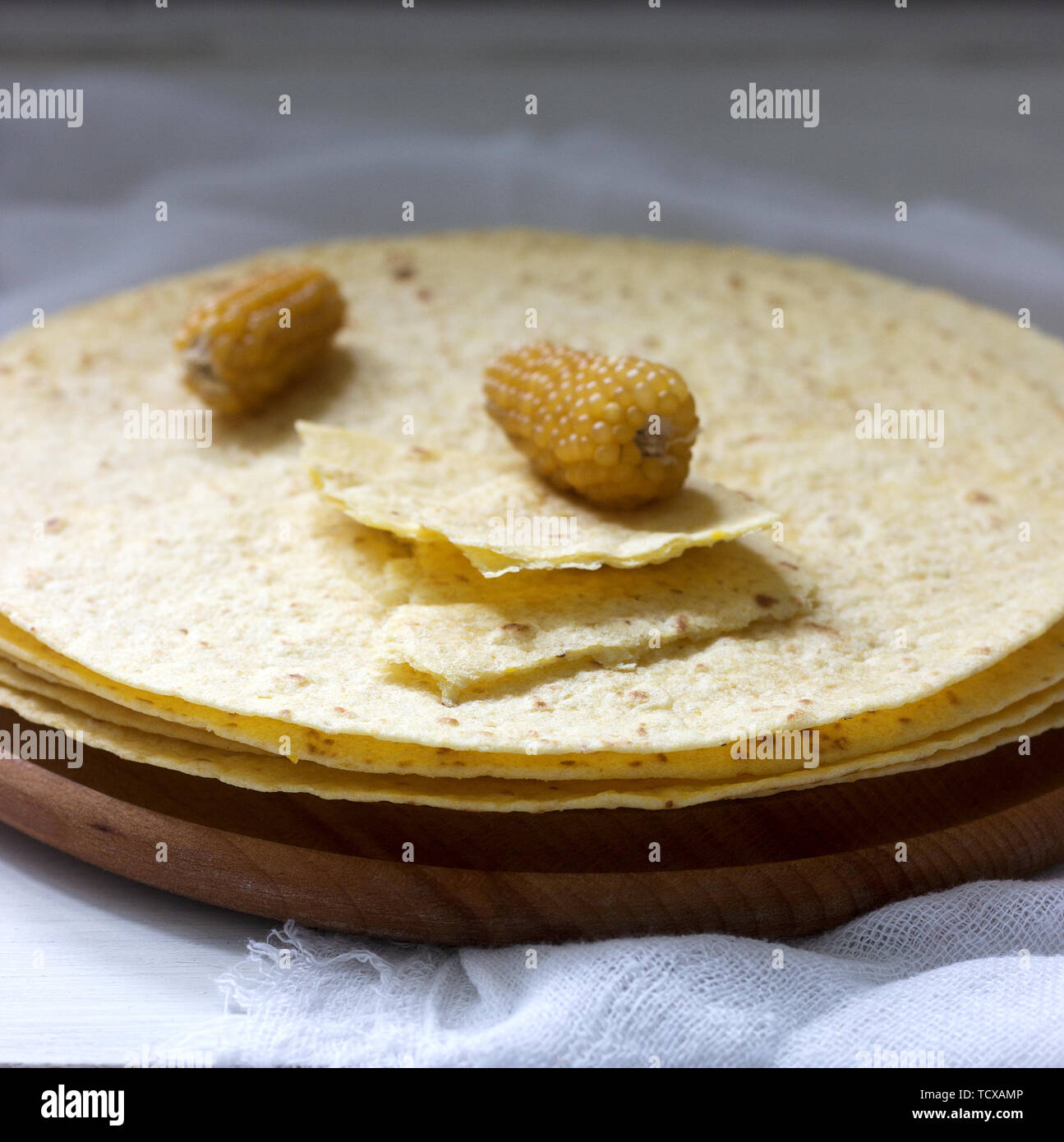 https://c8.alamy.com/comp/TCXAMP/a-stack-of-round-corn-tortillas-on-a-wooden-board-and-corncobs-selective-focus-TCXAMP.jpg