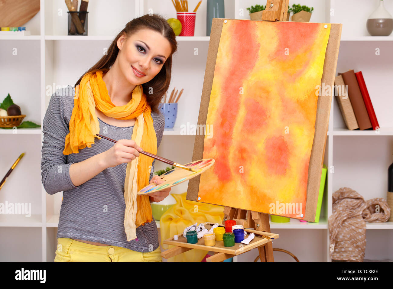 beautiful young woman painter at work on room interior background