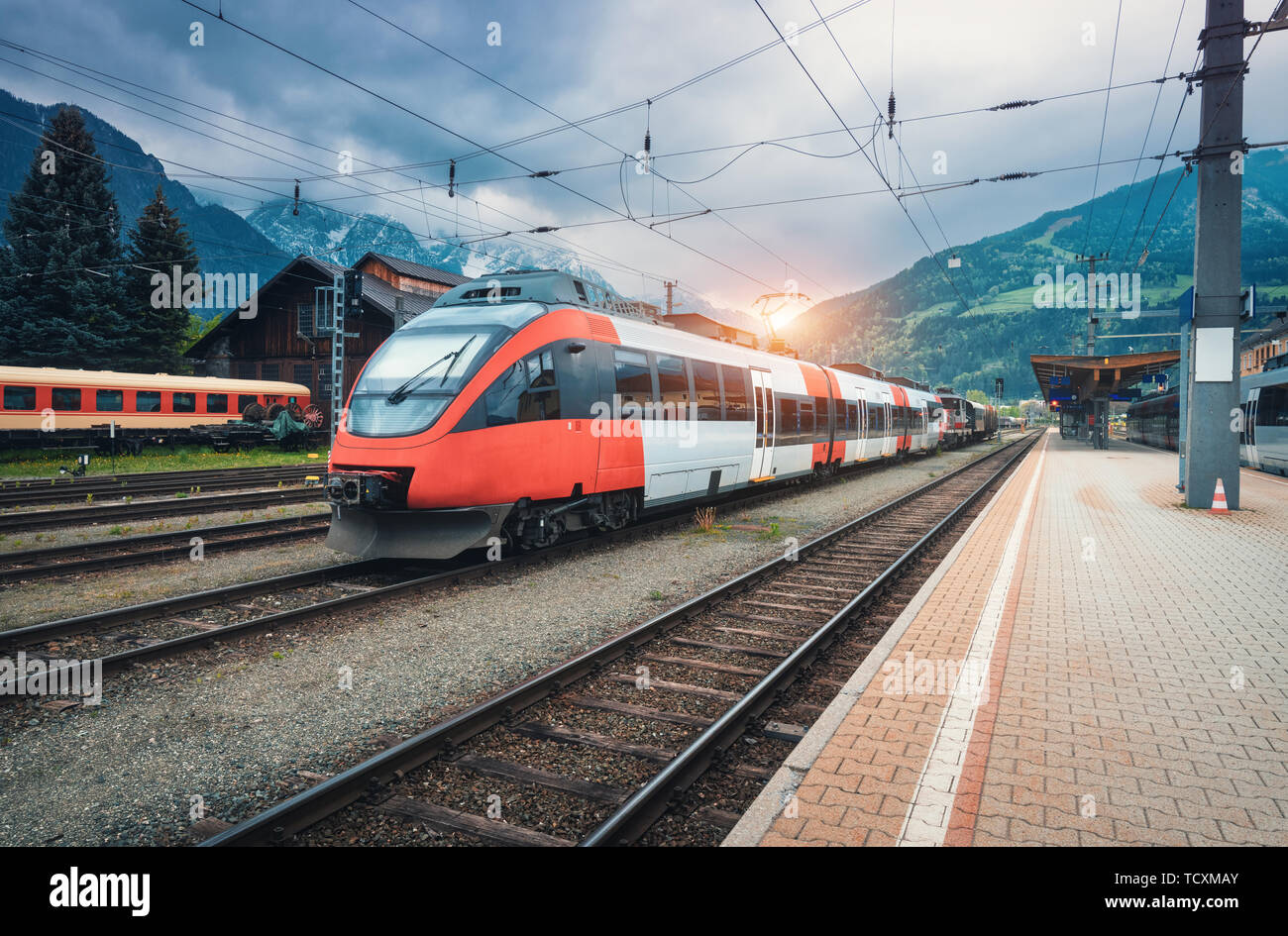 High speed train on the railway station in mountains at sunset Stock Photo