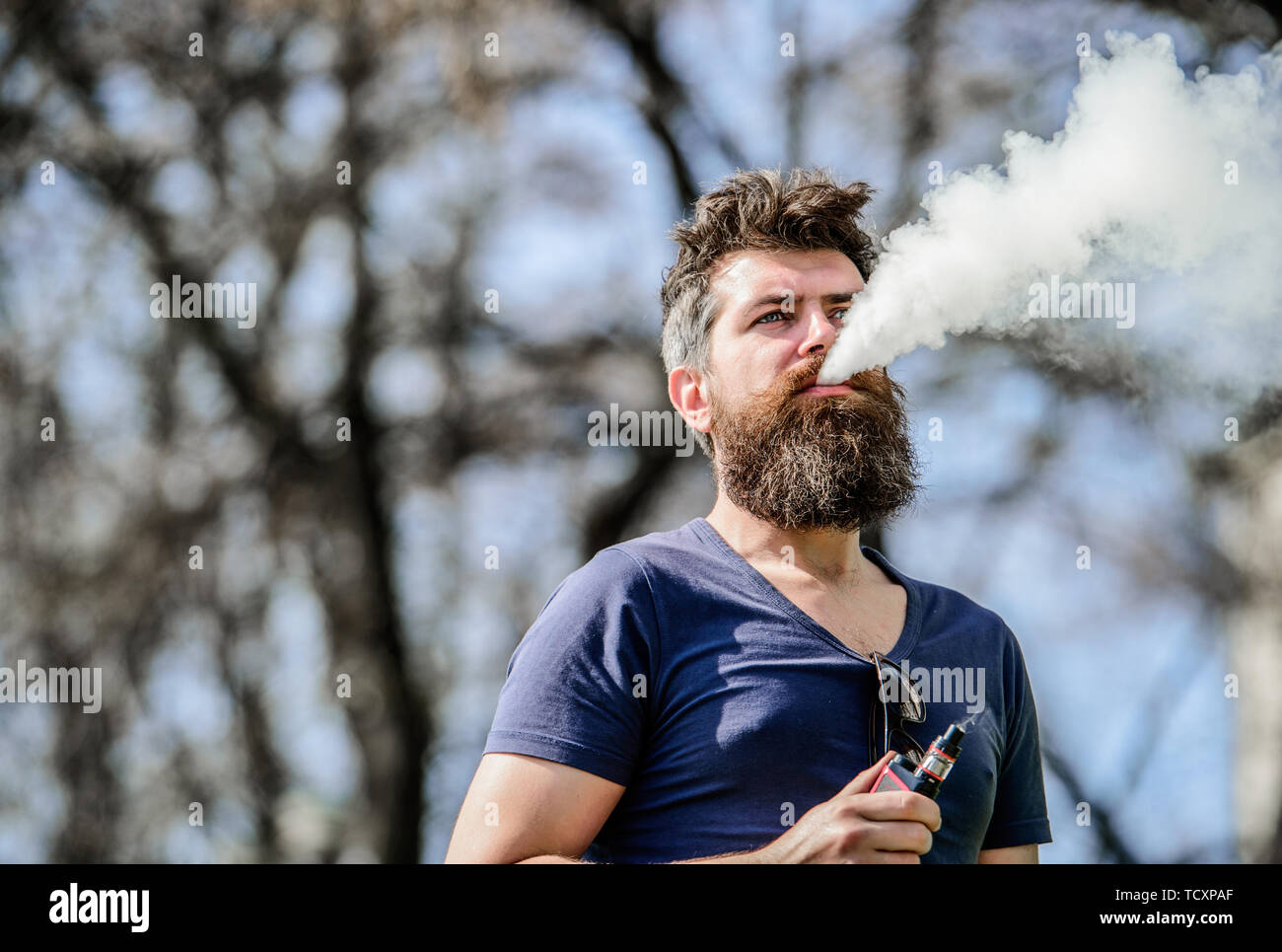 Stress relief concept. Bearded man smoking vape. Smoking electronic  cigarette. Man long beard relaxed with smoking habit. Man with beard and  mustache breathe out smoke. White clouds of flavored smoke Stock Photo -