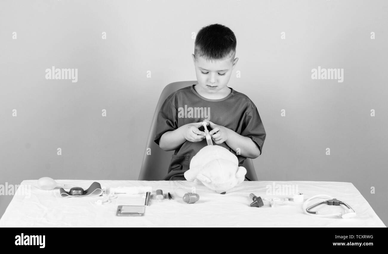 Medical procedures for teddy bear. Medical examination. Medical education. Boy cute child future doctor career. Health care. Kid little doctor busy sit table with medical tools. Medicine concept. Stock Photo