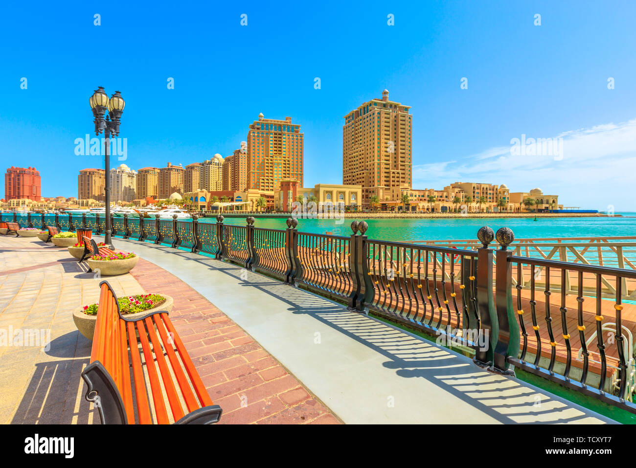Benches and palm trees along marina walkway promenade in Porto Arabia