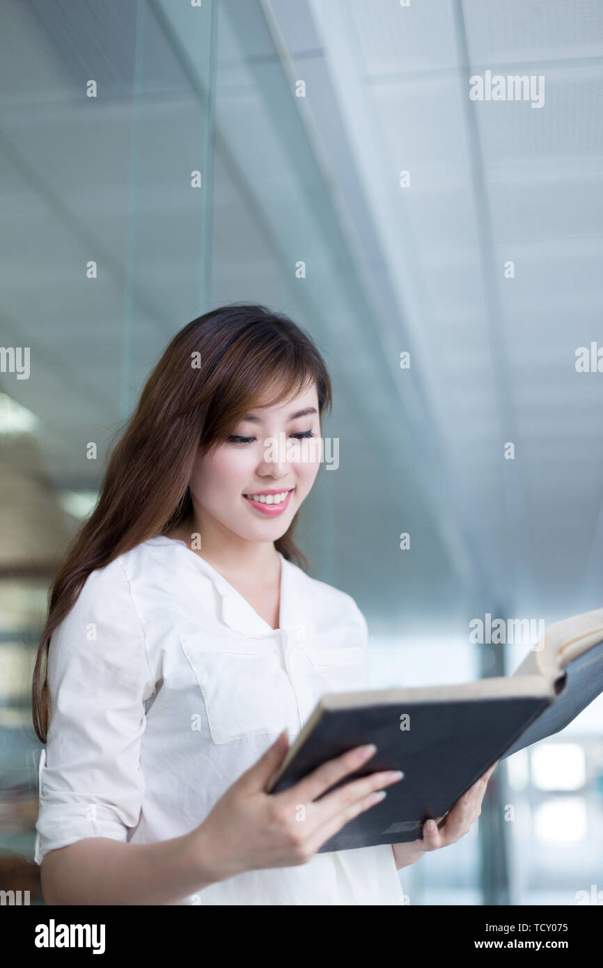 Asian beautiful female student holding book in library Stock Photo - Alamy