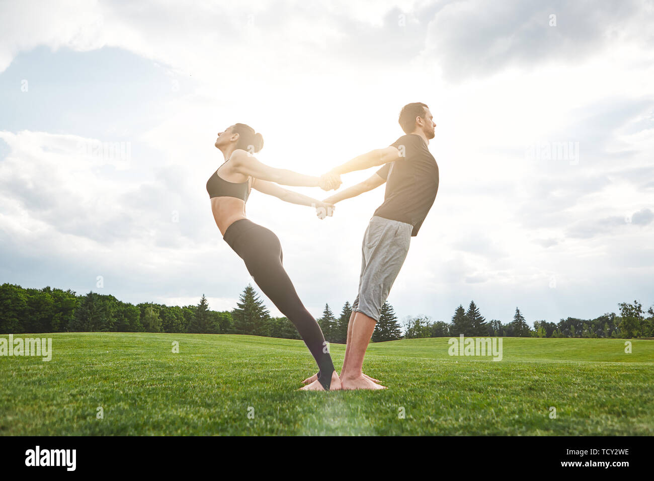 Yoga in pair. Beautiful young couple practicing acro yoga together and ...