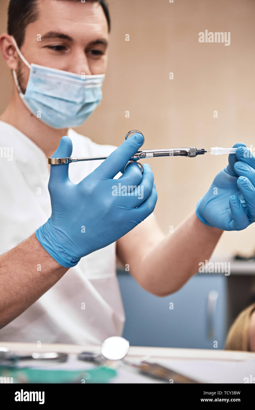 Male doctor with injection. Young dentist prepares a syringe for an injection. Dental treatment