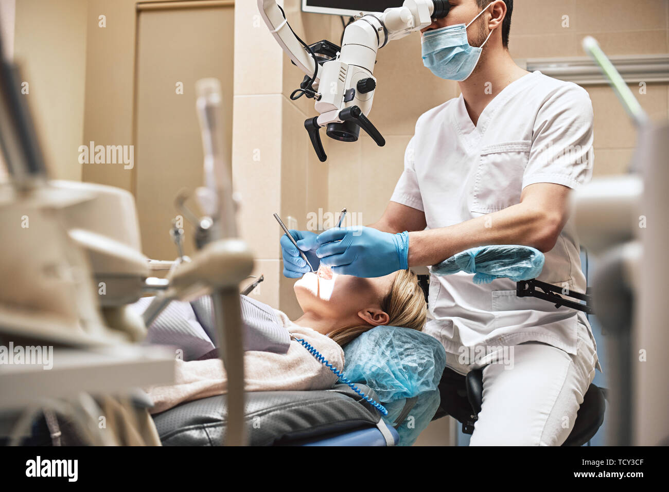 Male dentist wearing white uniform, looking into professional dental