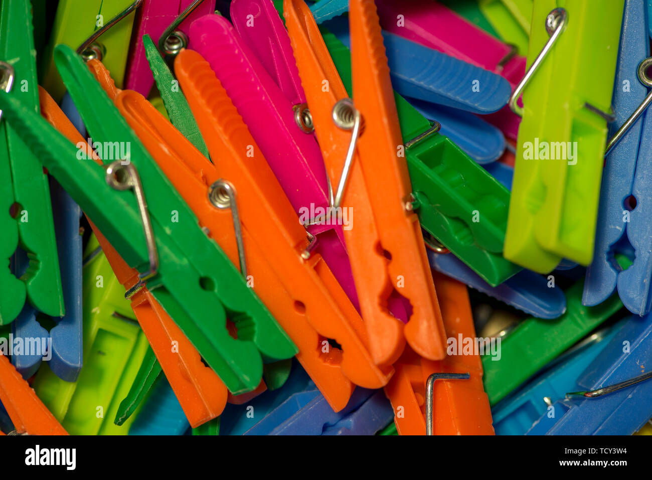 A handful of clothespins hanging clothes of various types of colors