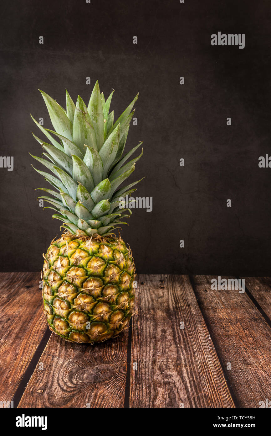 Pineapple Fruit photographed on a wooden table against a black slate background. Stock Photo