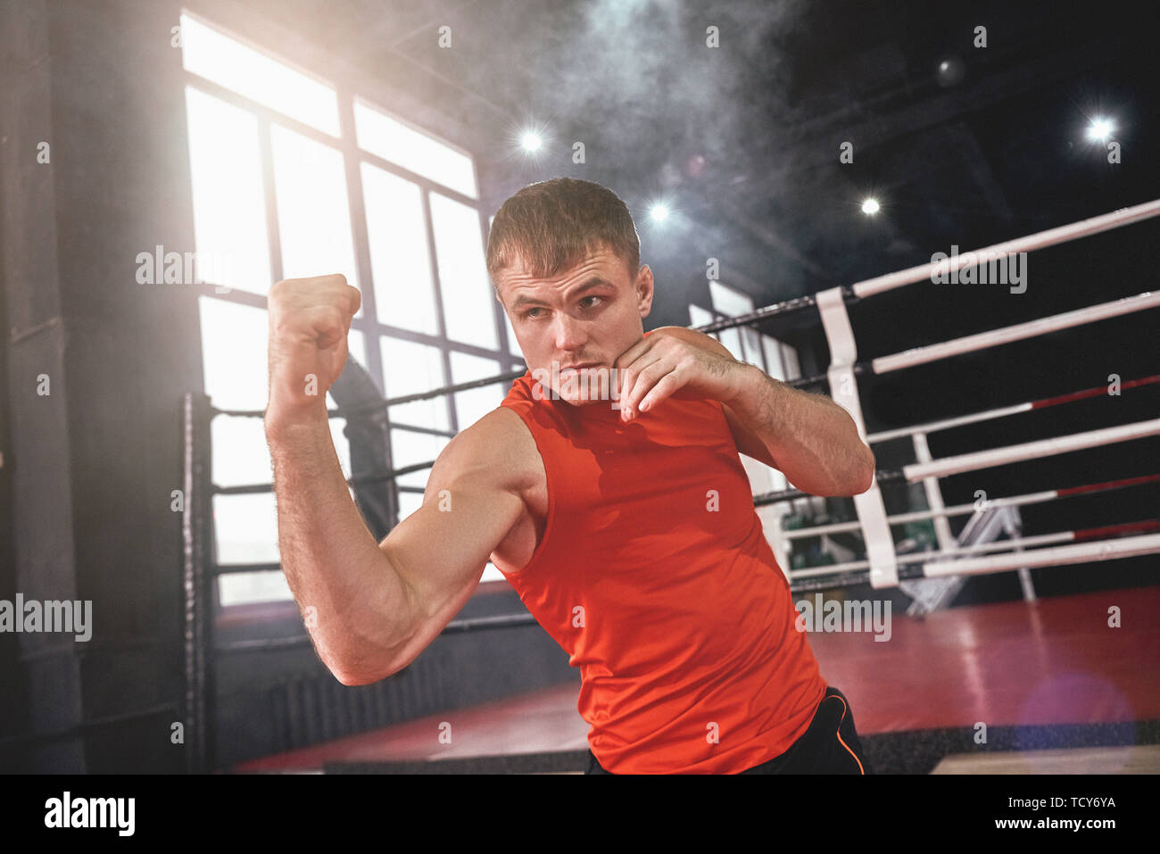 Focused muscular athlete in sports clothing throwing uppercut. Young ...