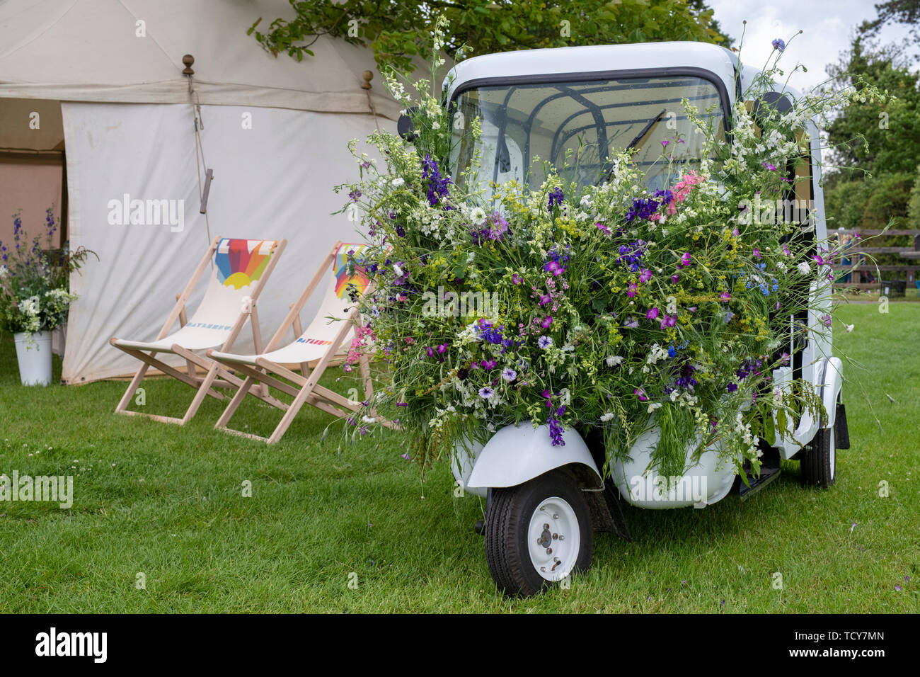 Indian rickshaw covered in wildflowers at Daylesford Organic farm summer festival. Daylesford, Cotswolds, Gloucestershire, England Stock Photo