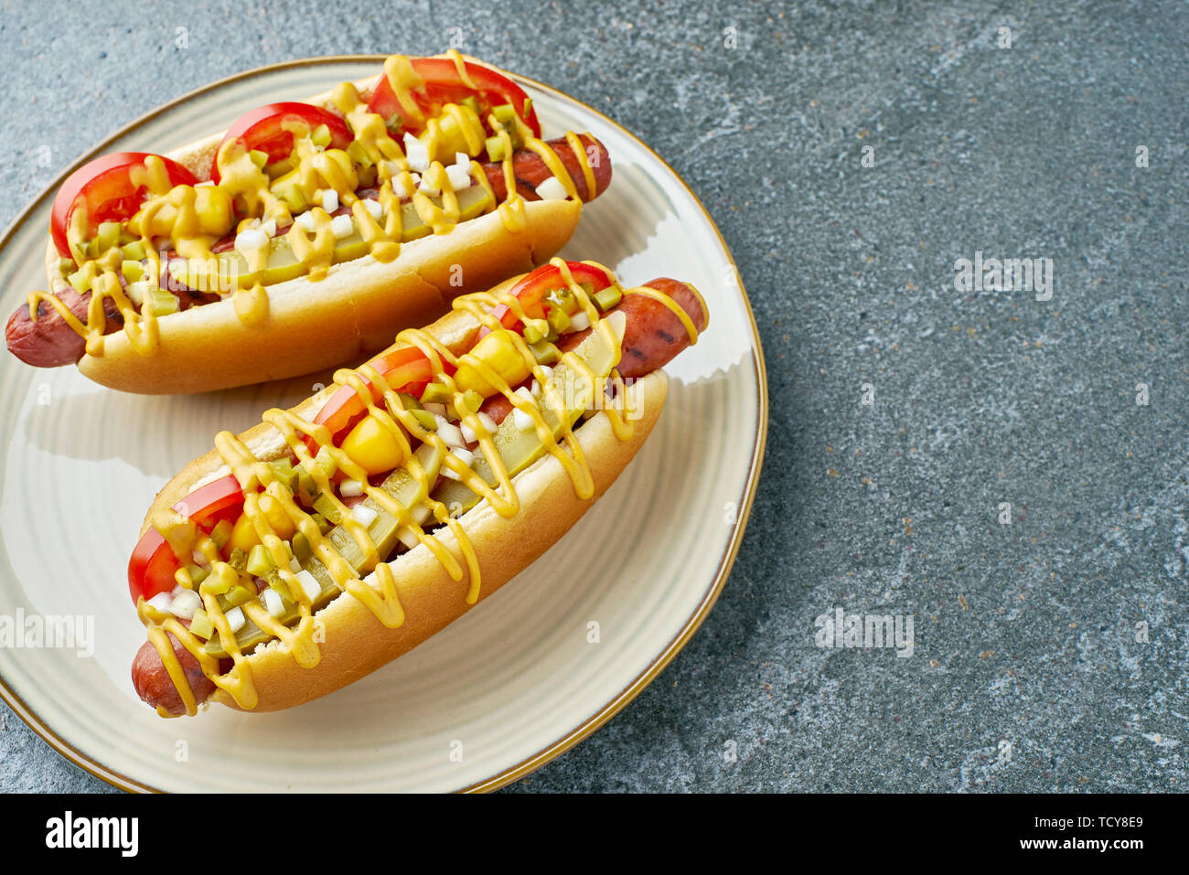 Dish with two hot dogs on stone table Stock Photo