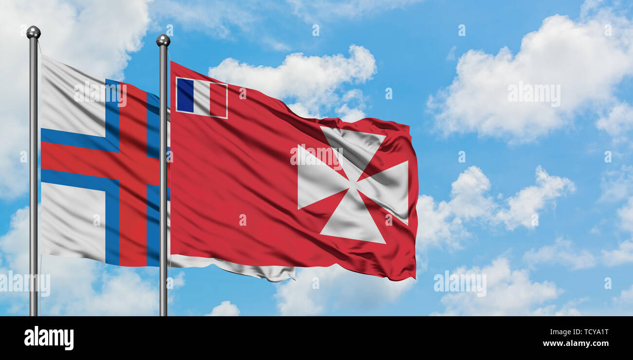Faroe Islands and Wallis And Futuna flag waving in the wind against white cloudy blue sky together. Diplomacy concept, international relations. Stock Photo