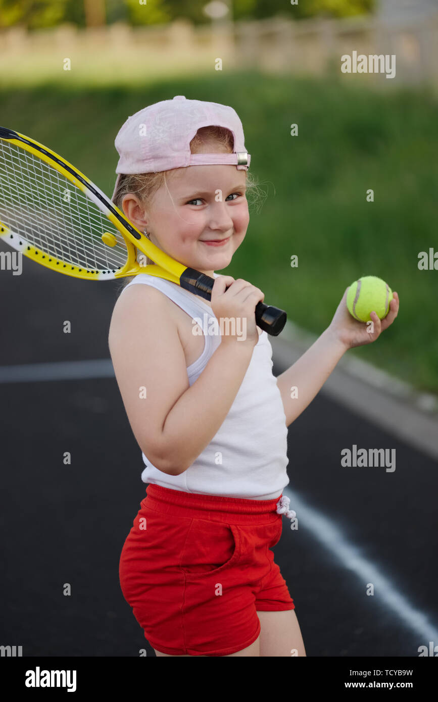 happy girl plays tennis on court outdoors Stock Photo