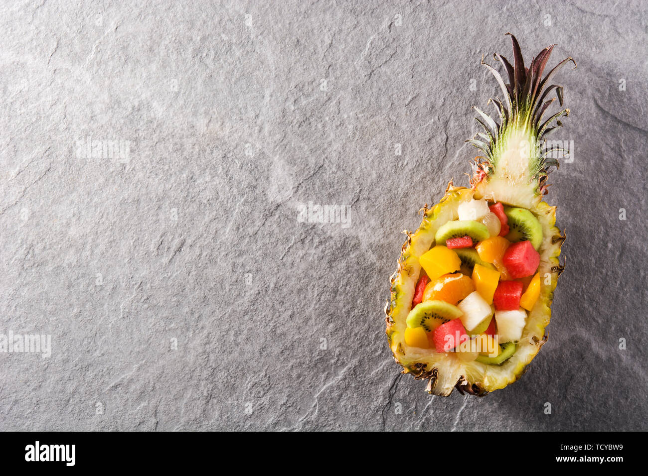 Mix fruit served inside pineapple on blue background Stock Photo
