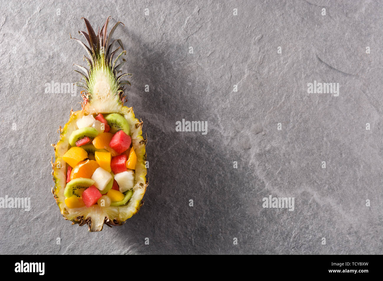 Mix fruit served inside pineapple on blue background Stock Photo