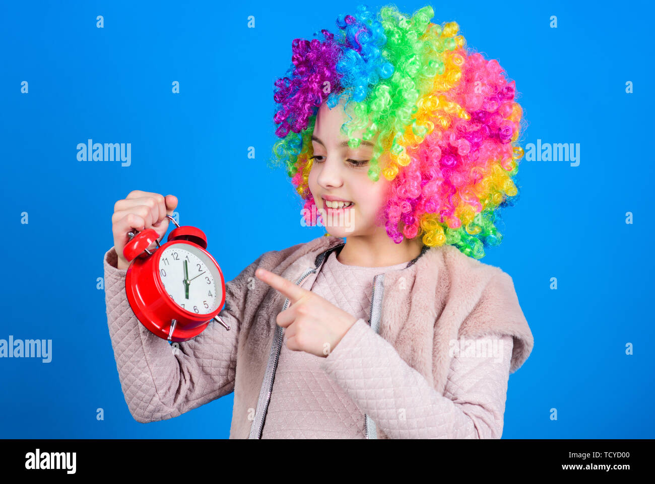 Its resting time. Happy little girl with colorful wig hair pointing at