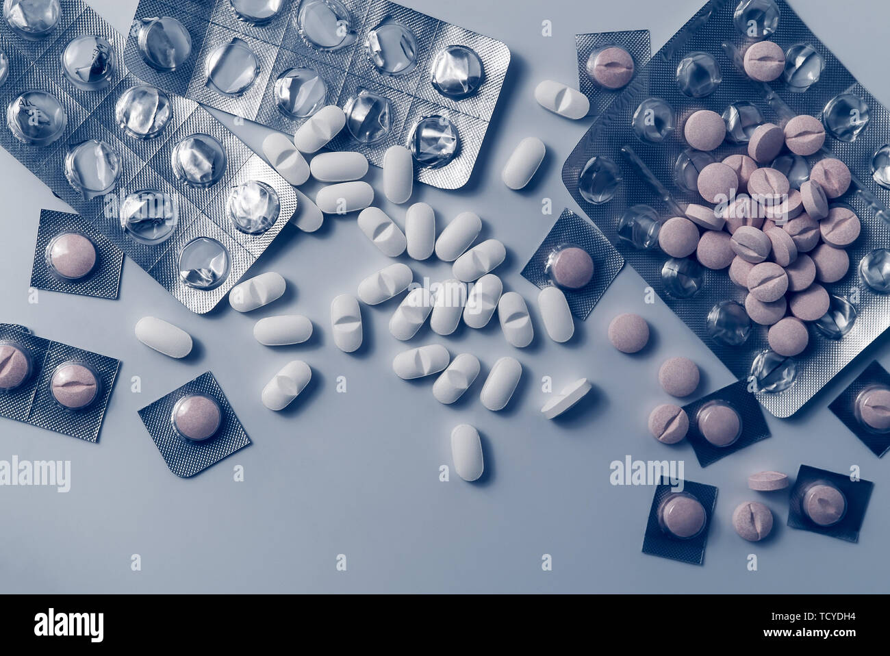 Top view of many prescription drugs, medicine tablets or vitamin pills and empty blister packs in blue color tone - Concept of opioids healthcare Stock Photo