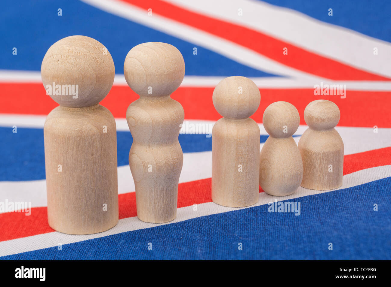 Small wooden abstract figures on Union Jack flag. For demographic of UK family life / British family unit, nuclear family, family households. Stock Photo