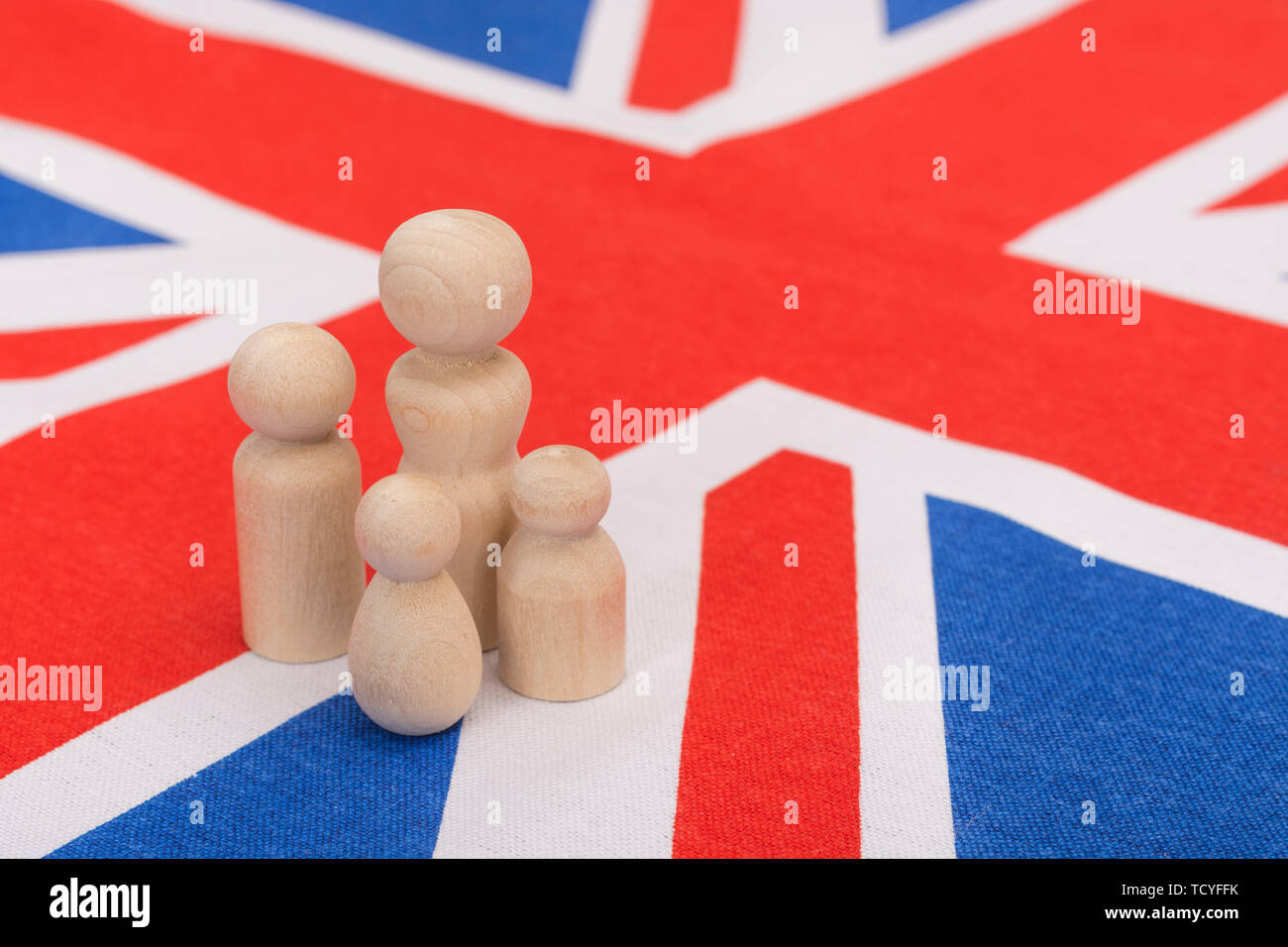 Small wooden abstract figures on Union Jack flag. For demographic of UK family life / British family unit, nuclear family, family households. Stock Photo