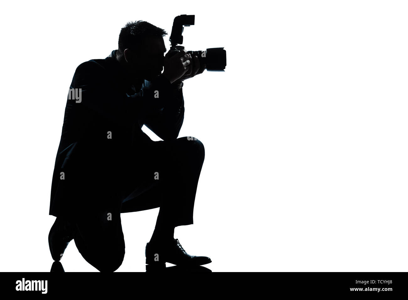 one caucasian man kneeling photographer full length silhouette in studio isolated on white background Stock Photo