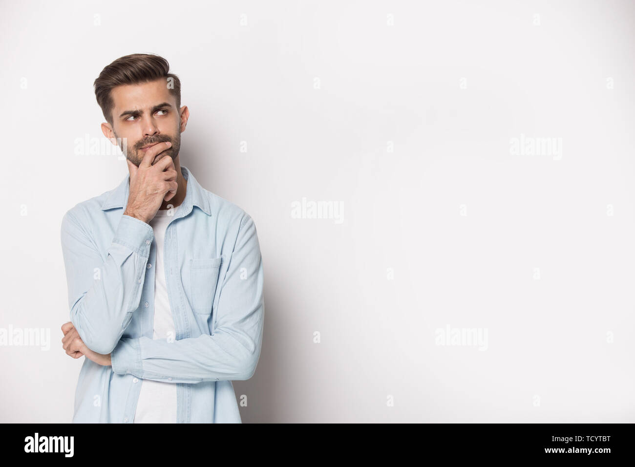 Pensive guy feeling doubtful pose isolated on white studio background Stock Photo